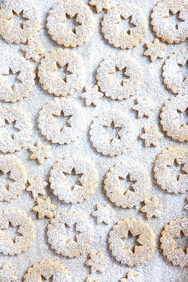 Baked linzer cookies dusted with powdered sugar on a baking sheet