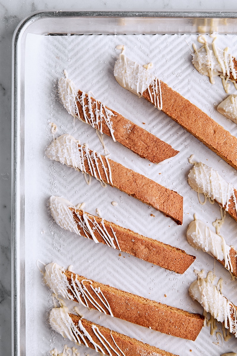 Biscotti dipped in white chocolate on baking sheet