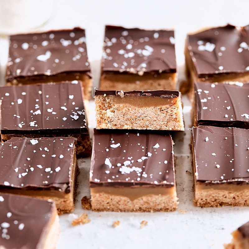 Layered chocolate caramel bars topped with chocolate and flaky salt