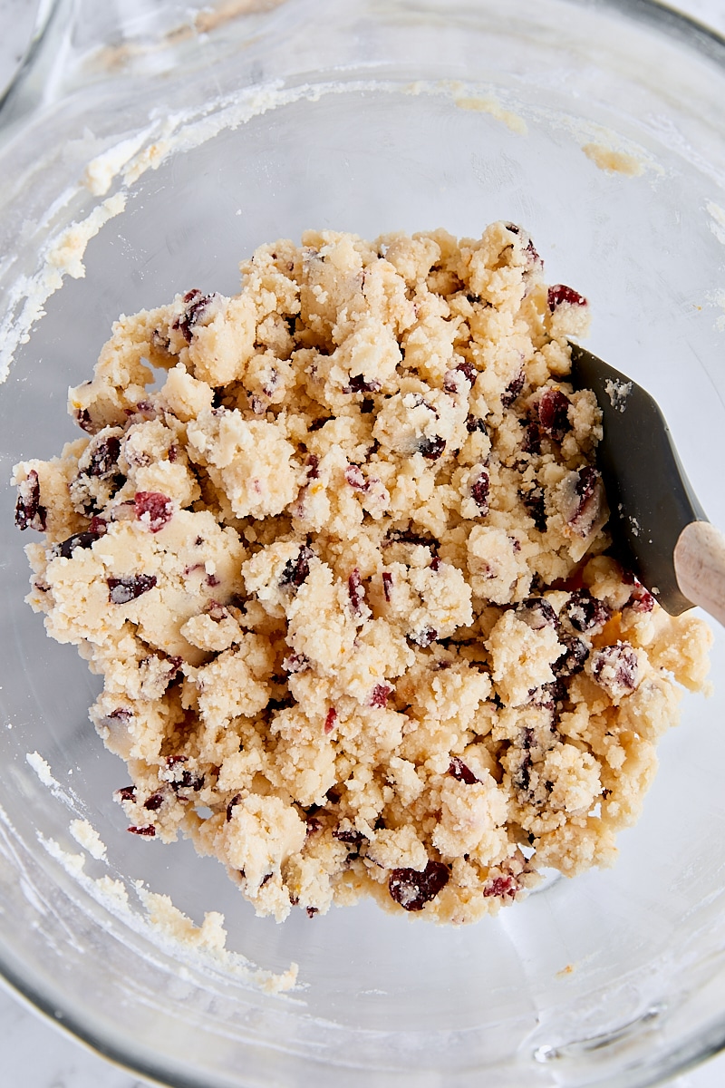 Crumbly shortbread dough with dried cranberries in glass mixing bowl