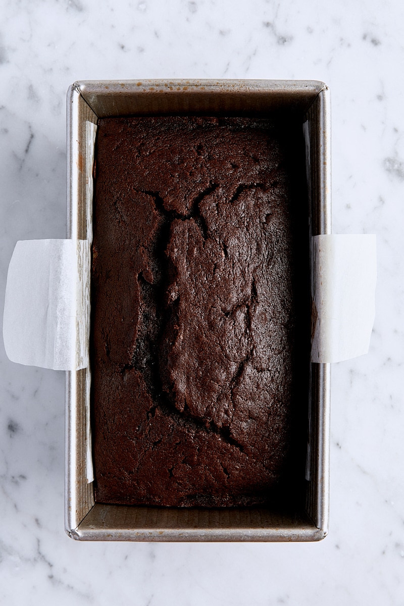 Baked triple chocolate loaf cake in parchment-lined loaf pan