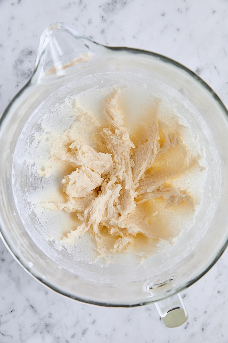 Vanilla and almond extracts mixed with butter and sugar in glass mixing bowl