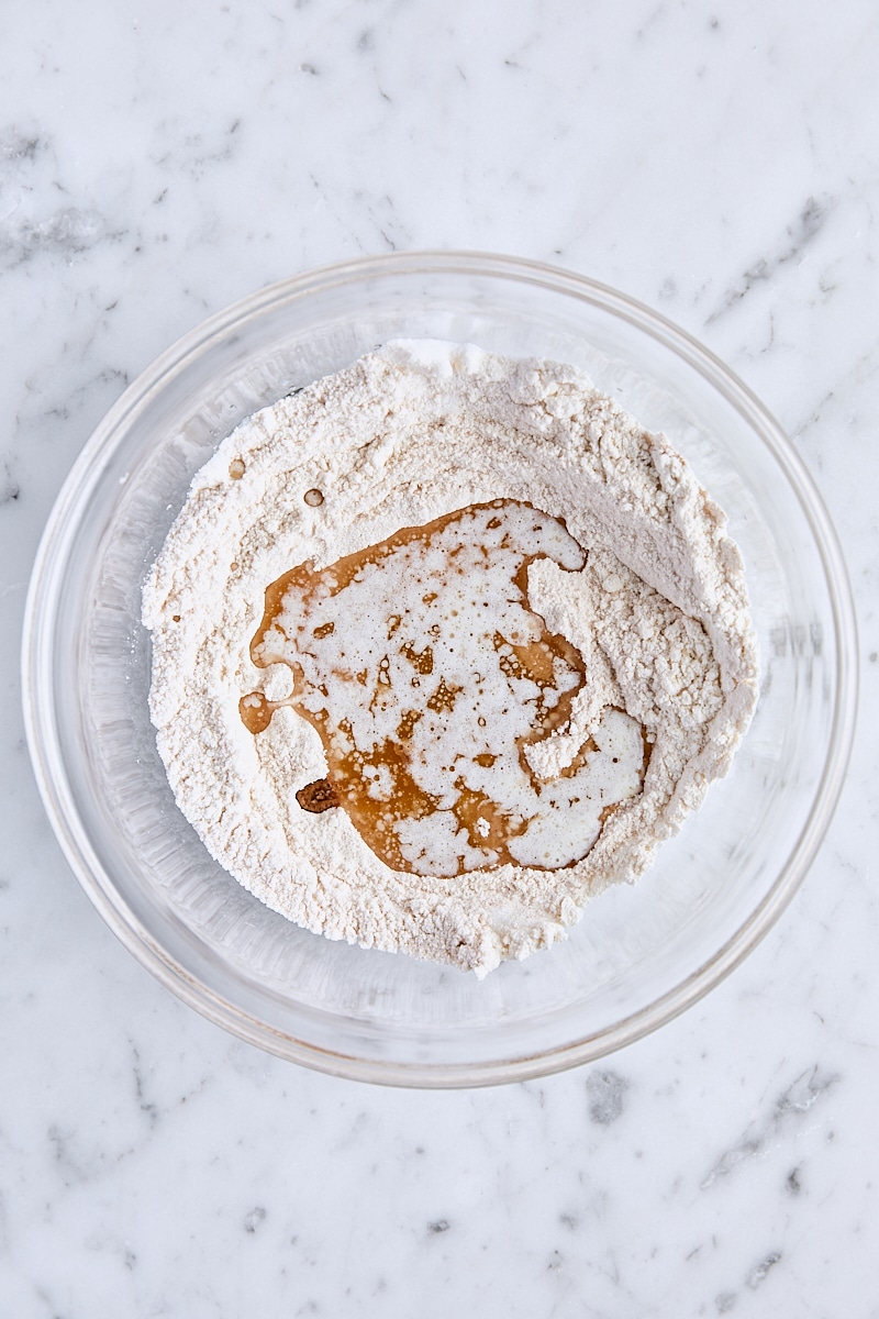 Melted butter and vanilla added to crumb topping ingredients in glass bowl