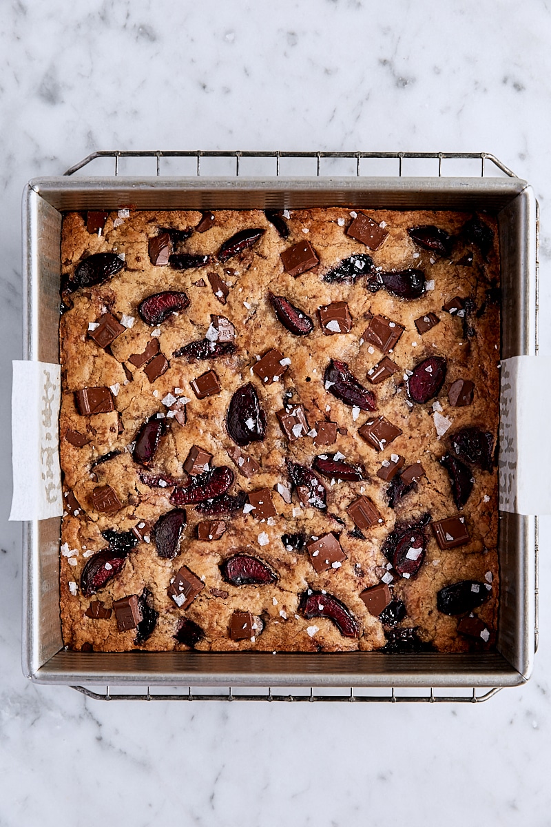 Baked cherry chocolate blondies in parchment-lined square pan