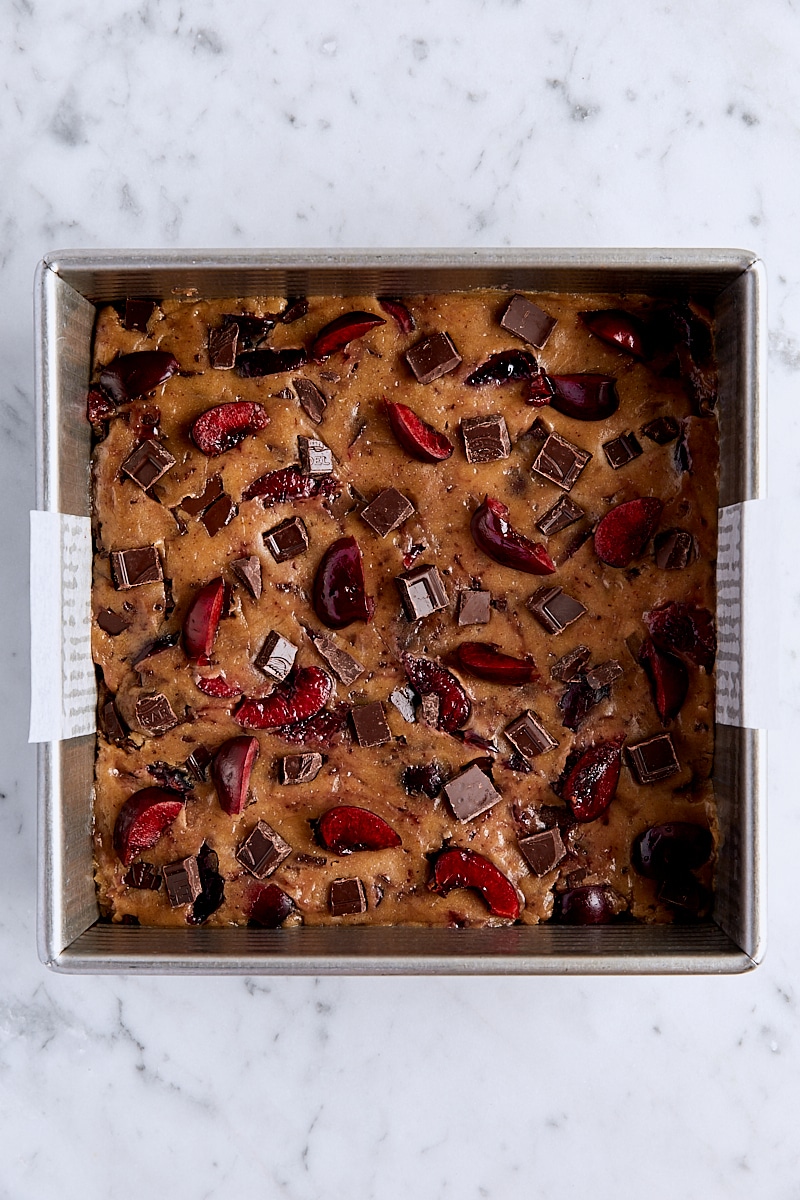 Cherry chocolate blondie batter in parchment-lined square pan