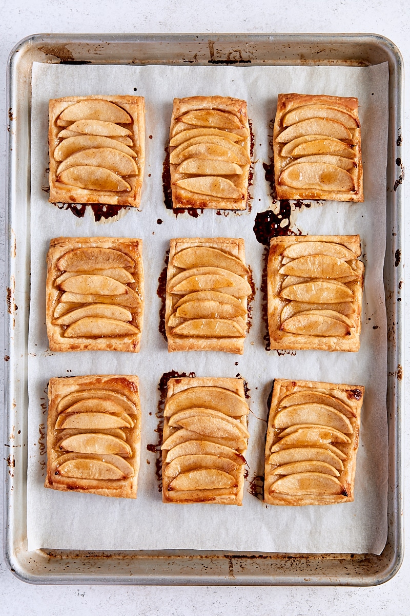 Baked puff pastry apple tarts on parchment-lined baking sheet