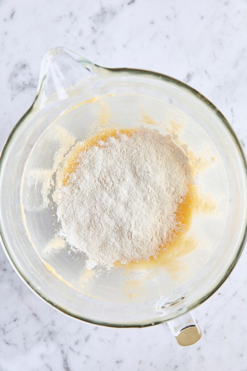 Dry ingredients added to batter in glass mixing bowl
