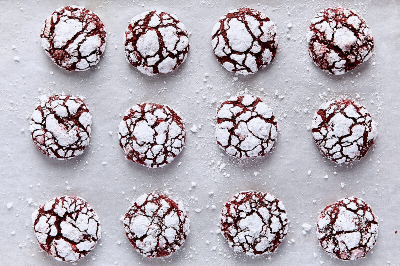Baked red velvet crinkle cookies on parchment-lined baking sheet