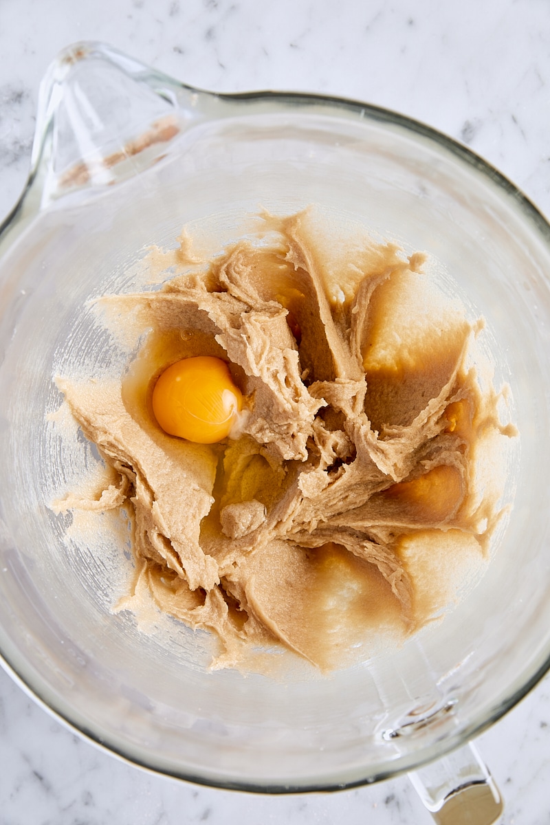 Egg added to cookie dough in glass mixing bowl
