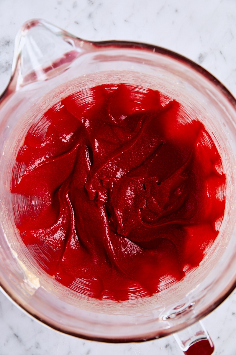 Red gel food coloring added to cookie dough in glass mixing bowl