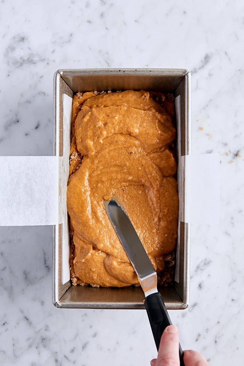 Spreading pumpkin bread batter over the streusel layer with an offset spatula