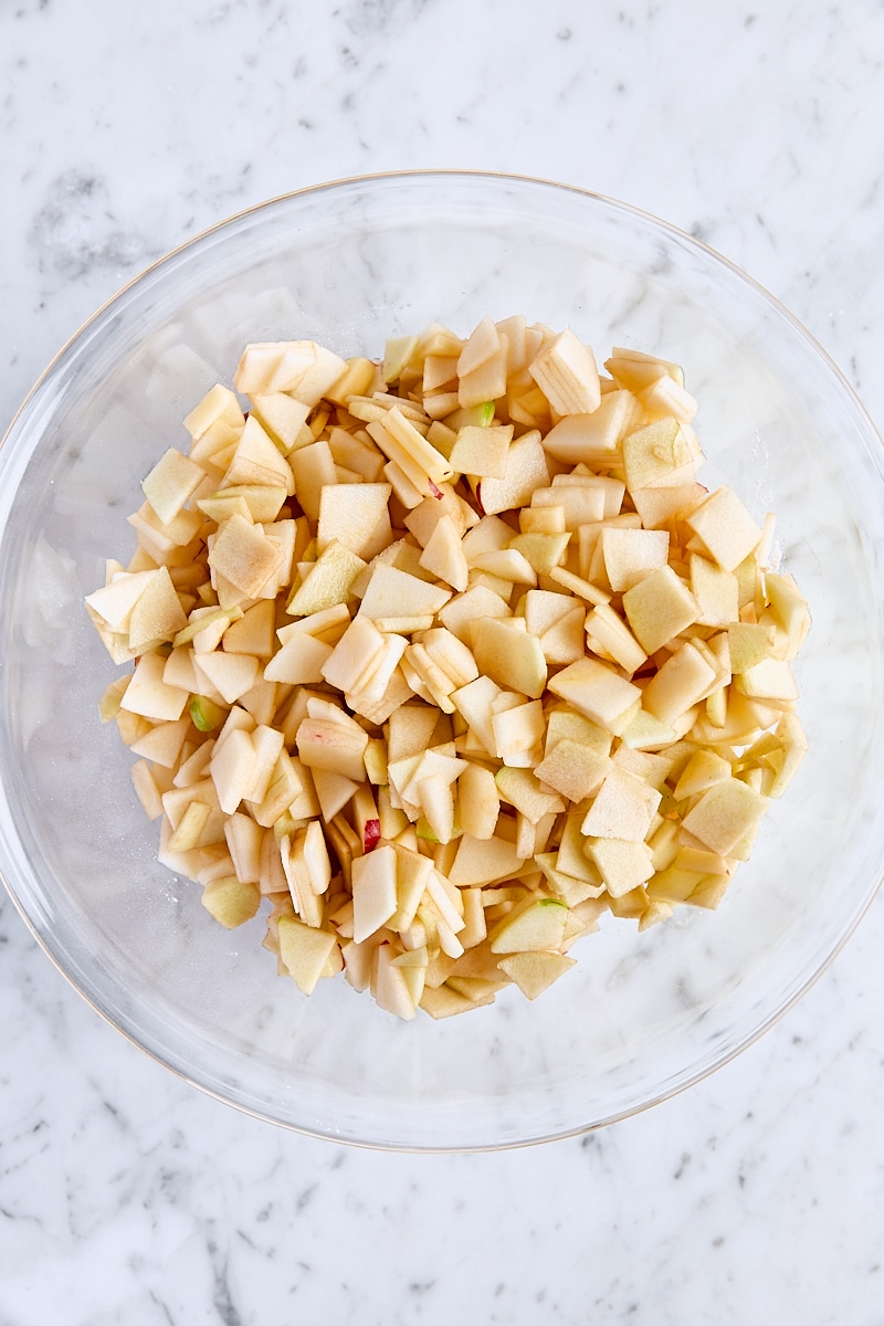 Apples added to sugar mixture in large glass bowl