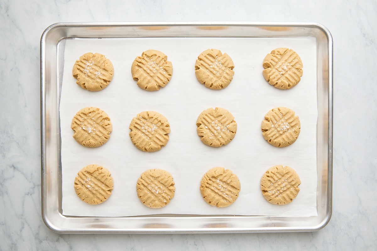 Baked cookies topped with flaky salt on parchment-lined baking sheet