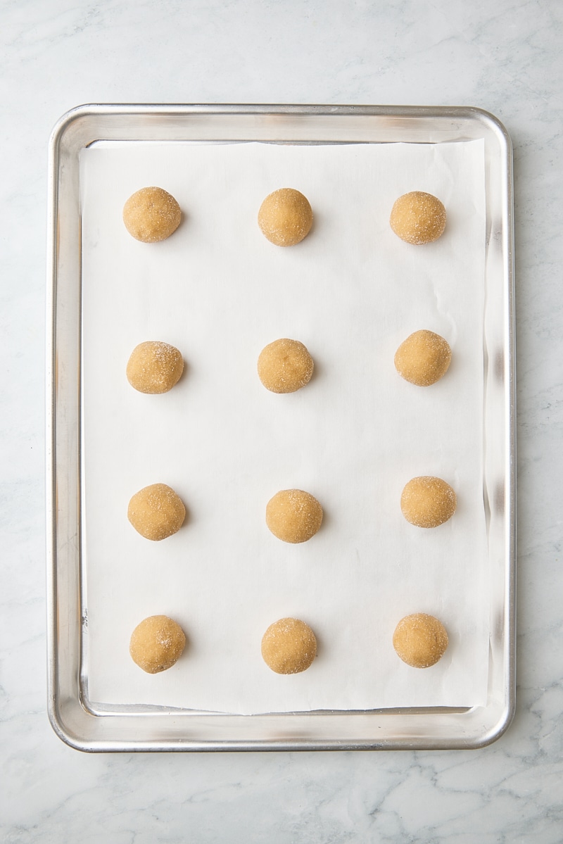 Peanut butter cookie dough balls scooped onto parchment-lined baking sheet
