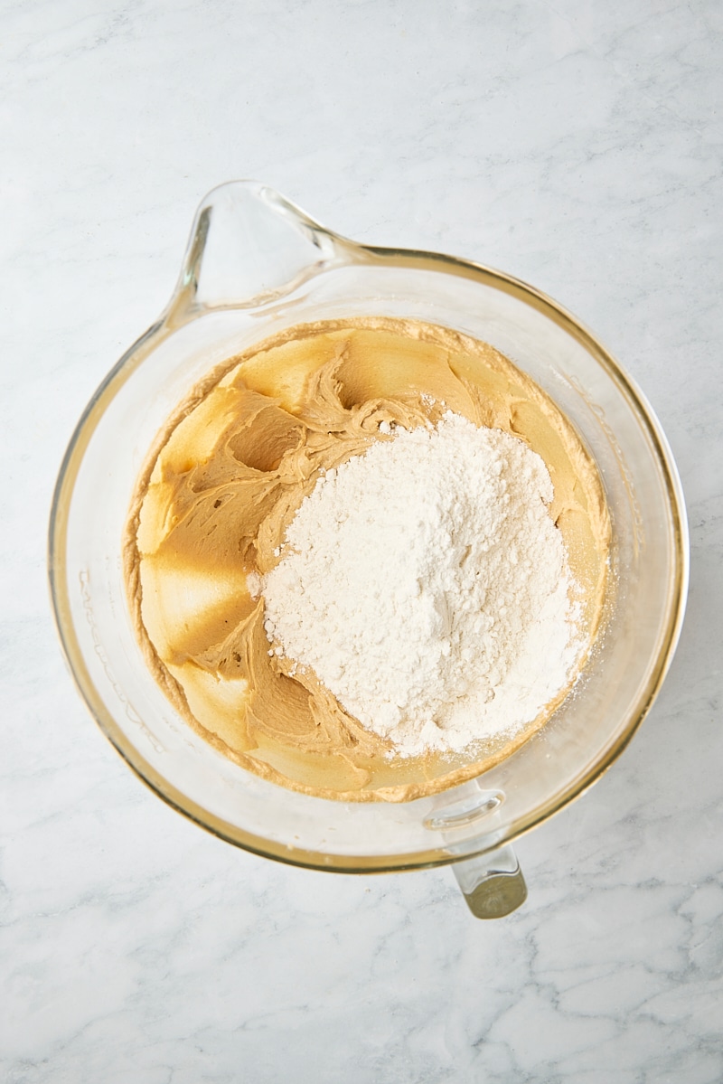 Flour mixture added to cookie dough in glass mixer bowl