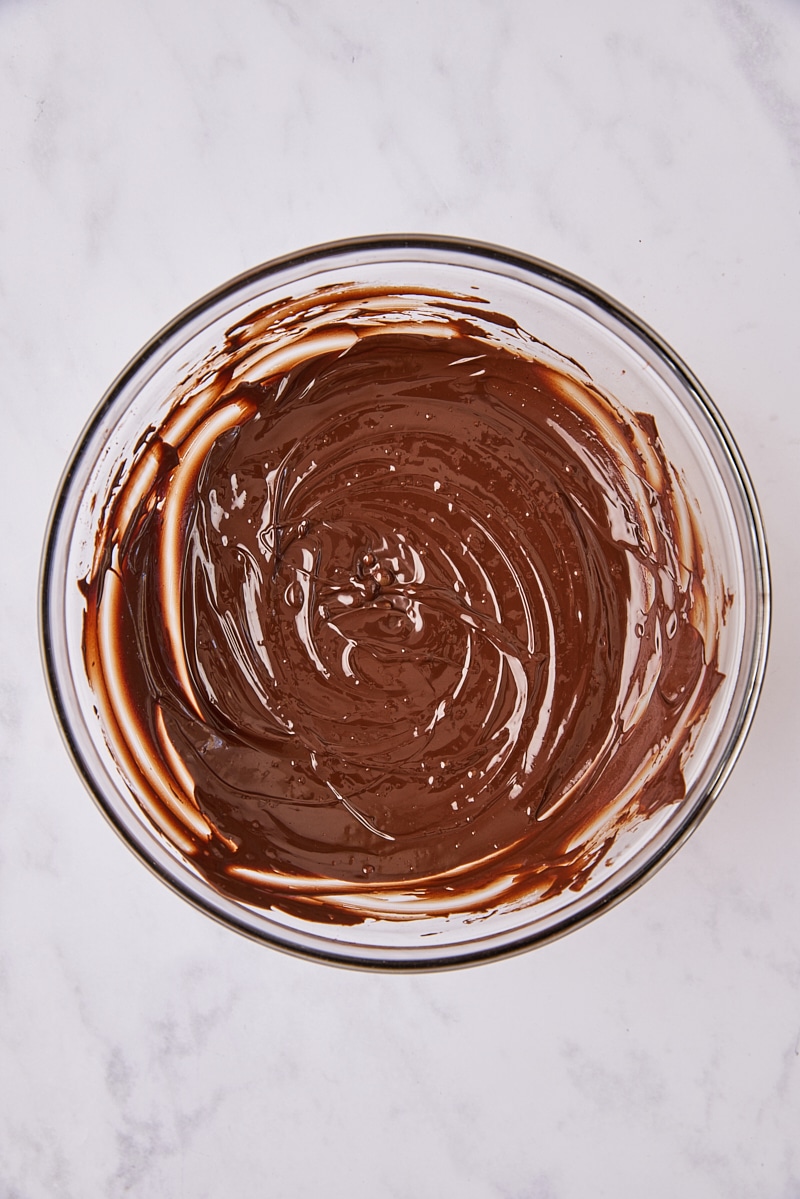 Cocoa powder whisked into melted chocolate in glass bowl